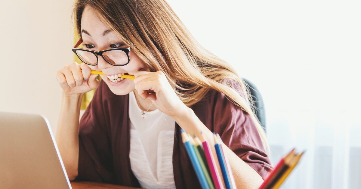 A woman with glasses biting a pencil because she is worried about her HRIS business case